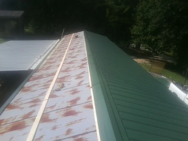 Old rusted panels beside newly installed green metal roofing — Wind Damage Roof Repair by Roofing Brothers in Green Valley