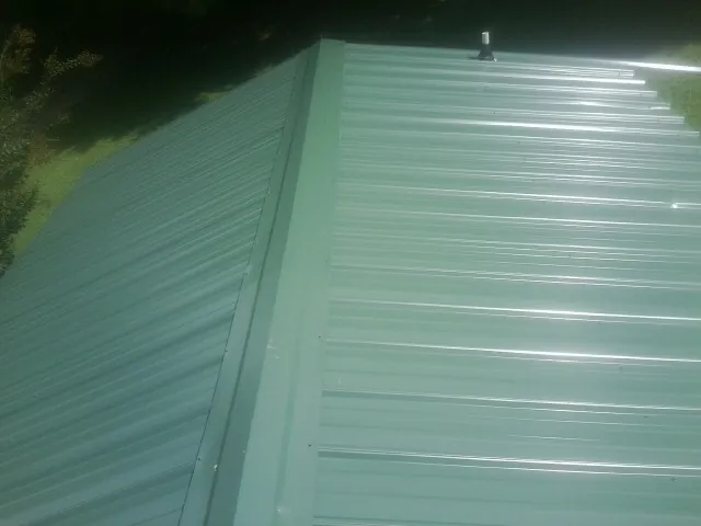 New green metal panels meeting at the ridge of a roof — Flat Roof Repair work by our crew in Green Valley