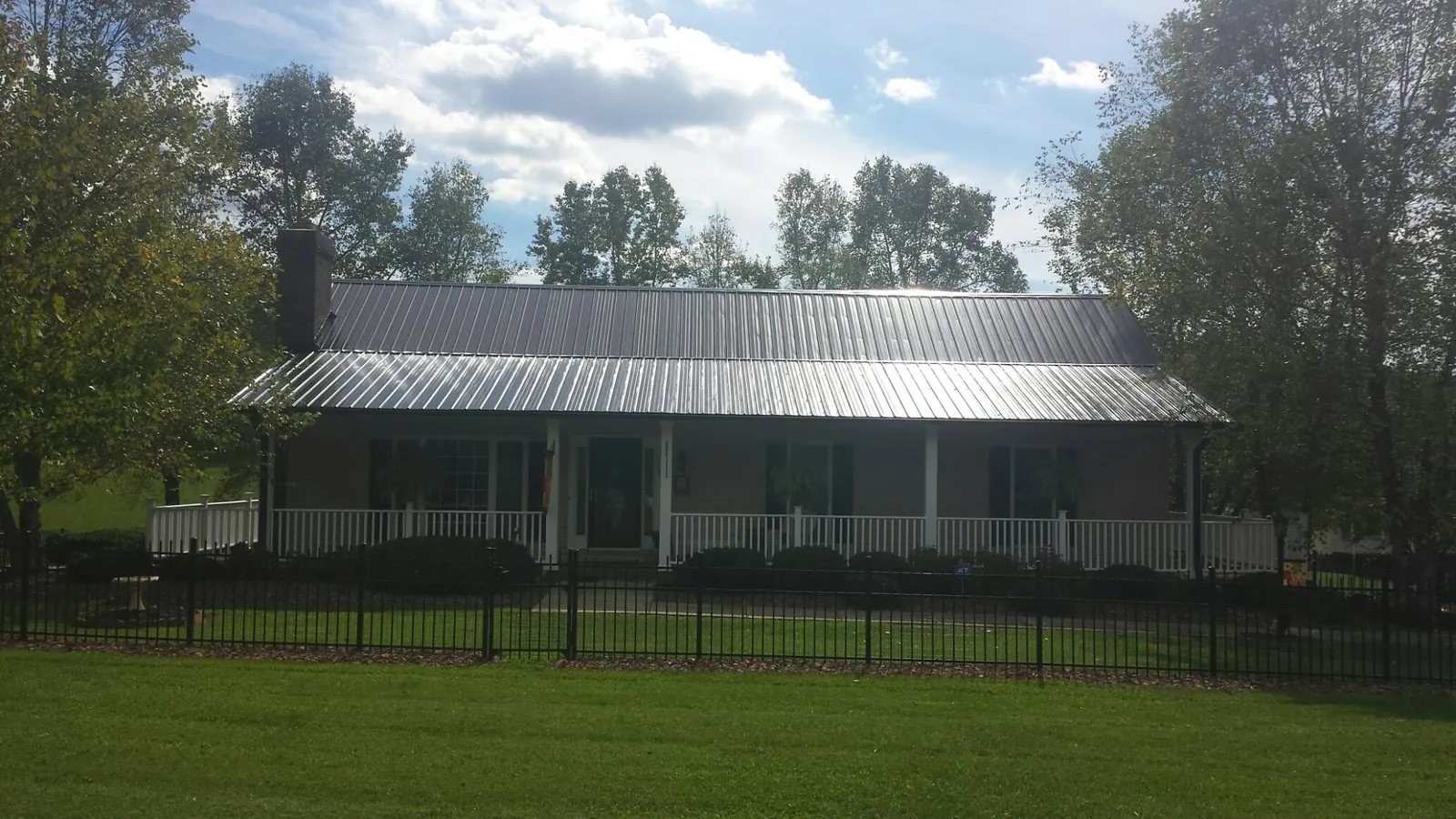 Gray metal roof on a brick ranch with a full width front porch — Gutter Guard Installation work by our crew in Green Valley