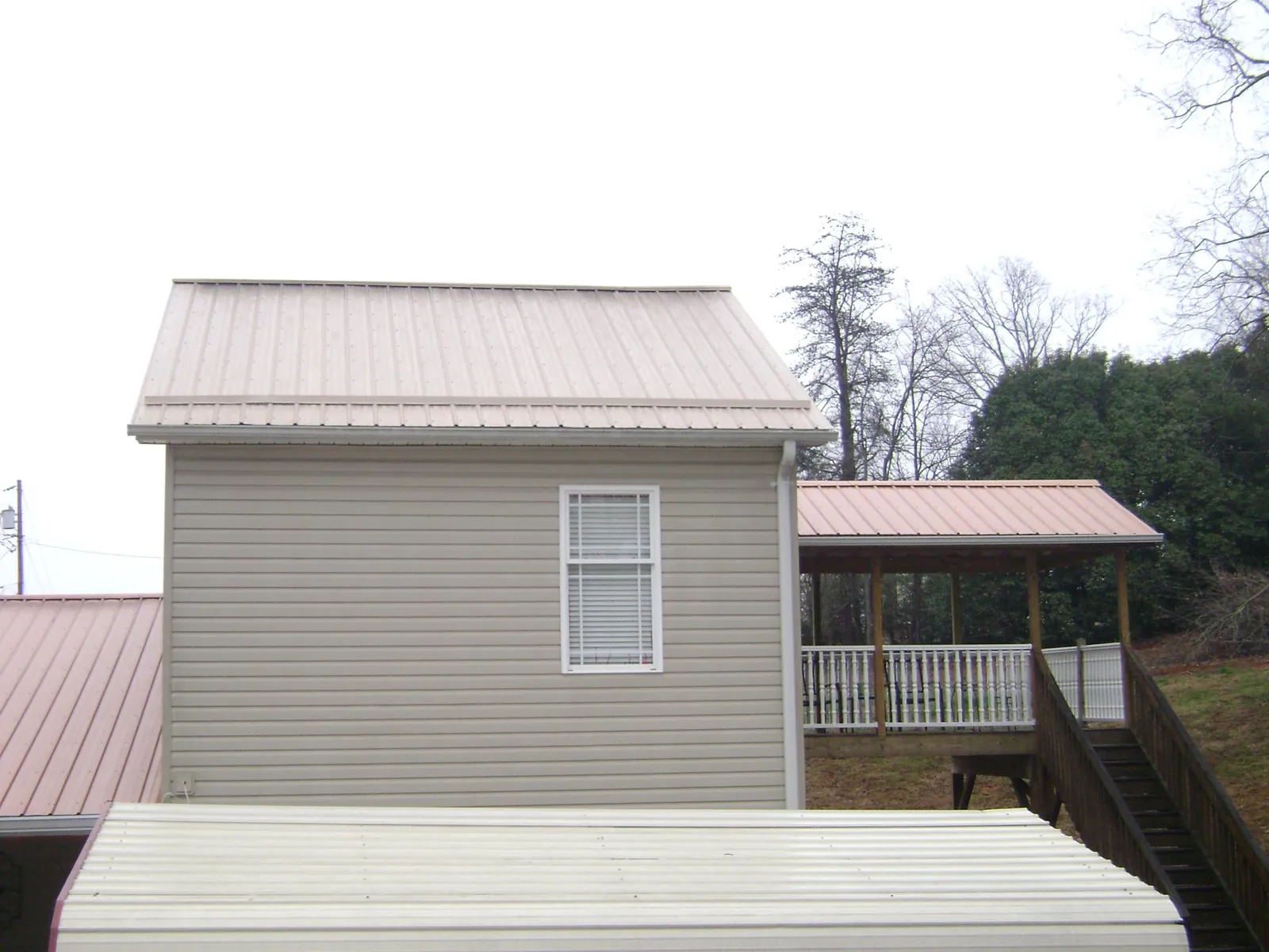 Tan metal roofs on a two story addition and attached porch, from a Roof Replacement job in Green Valley