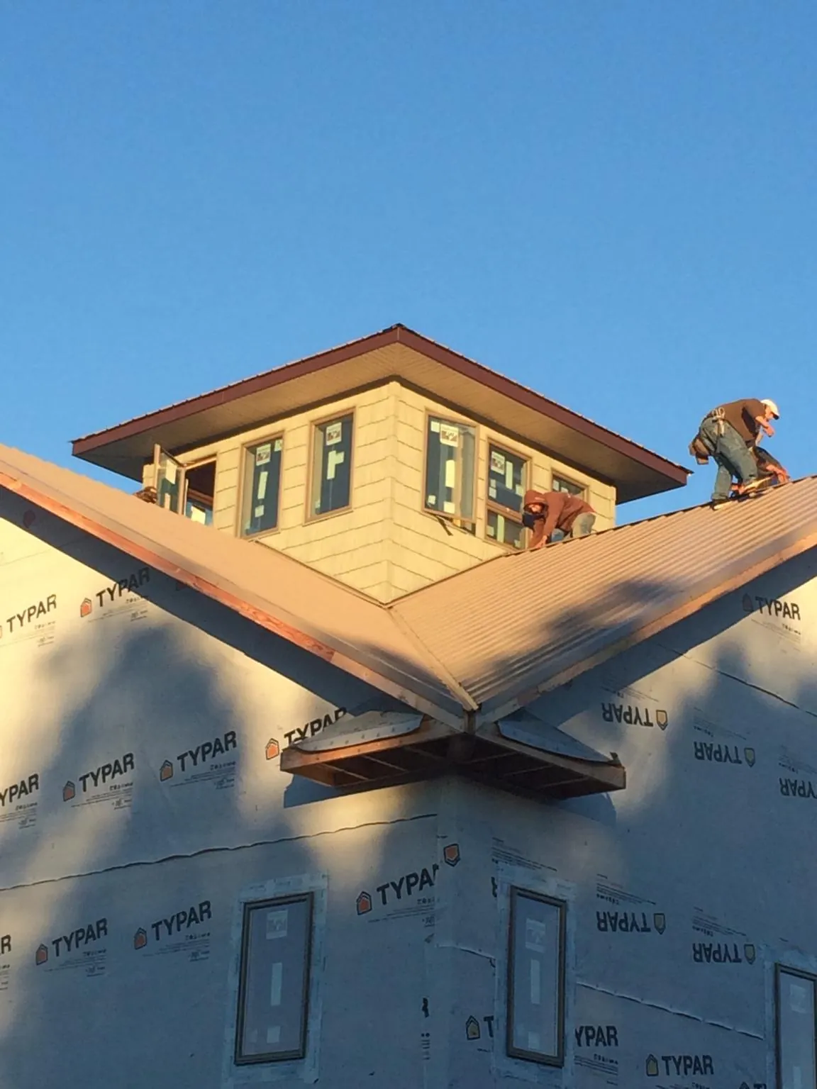 Roofers working around a rooftop cupola on a new metal roof at sunset — Roof Waterproofing in Green Valley by Roofing Brothers